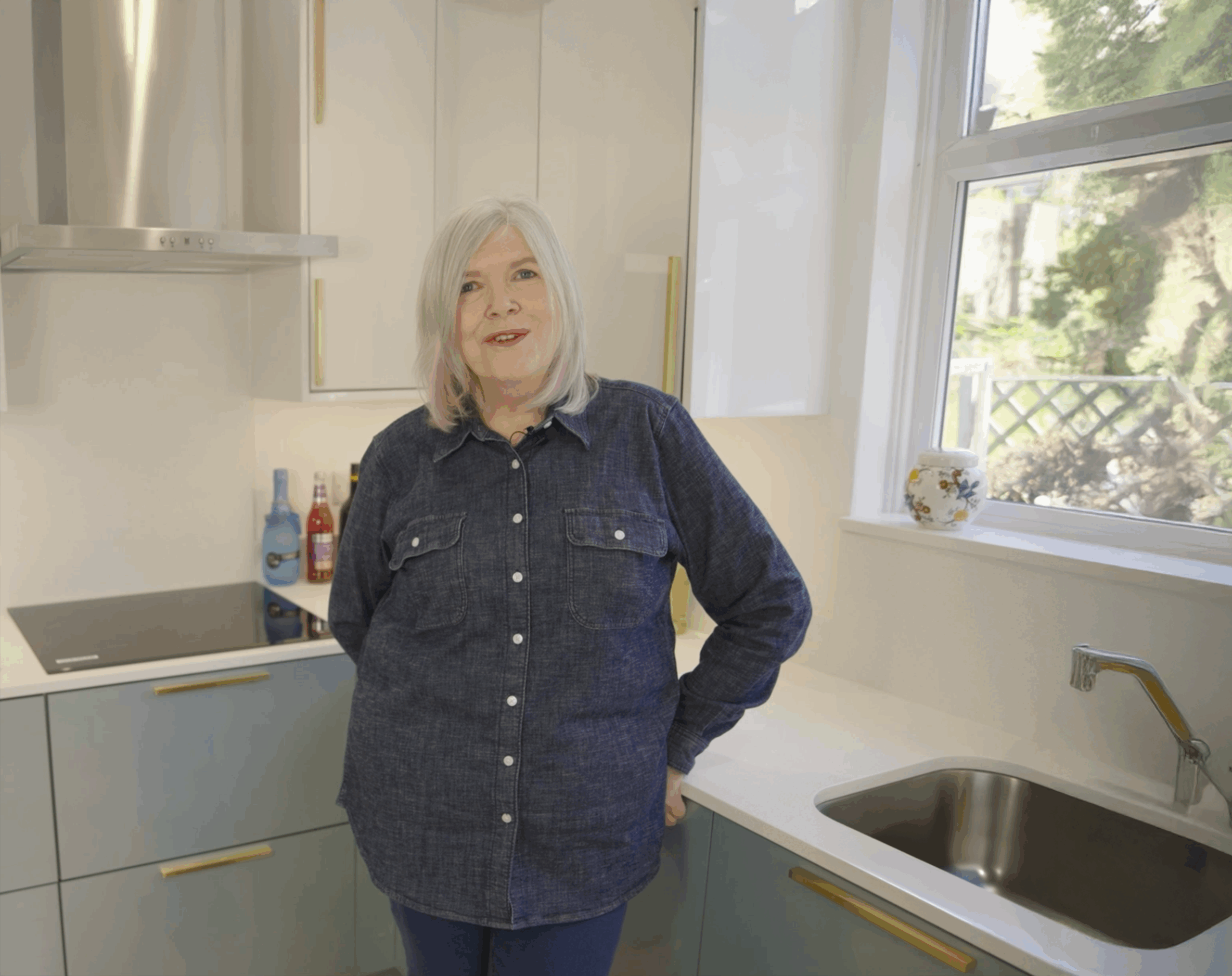 Anita in her kitchen with Dover White Quartz worktops visible around the sink and corner run