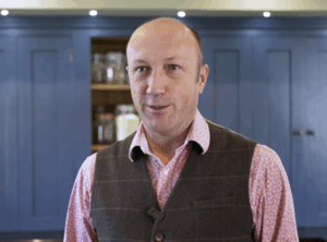 Testimonial video still of a customer speaking in a fitted kitchen after an Absolute Black Granite worktop installation by Mayfair Worktops.