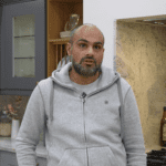 Testimonial video still of a customer speaking in their kitchen after an Ivory Fantasy Granite worktop installation by Mayfair Worktops.