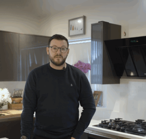 David standing in his kitchen beside an Imperial White Quartz worktop with a built-in gas hob