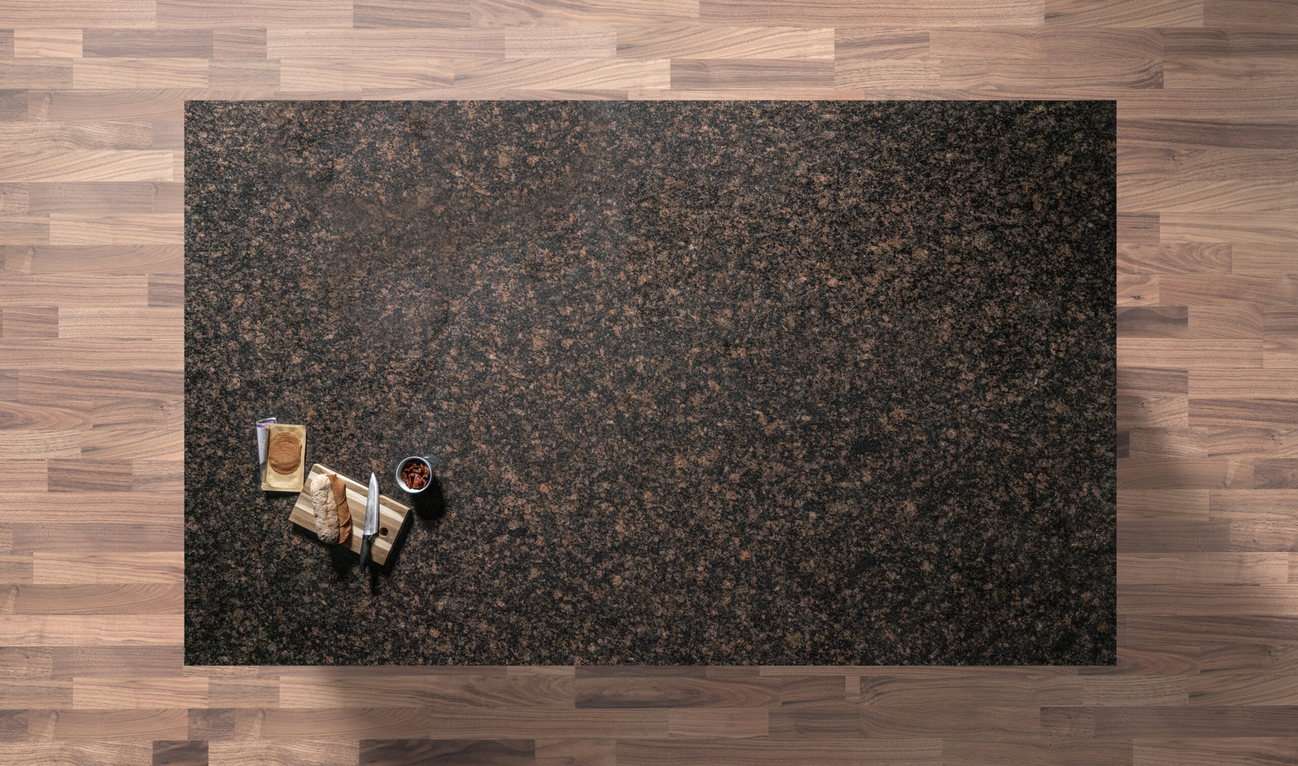 Overhead view of a Tan Brown Granite worktop showing a rich brown and black flecked pattern, photographed from above with a small styled tray in the corner.