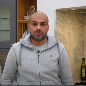 Testimonial video still of a customer speaking in their kitchen after an Ivory Fantasy Granite worktop installation by Mayfair Worktops.