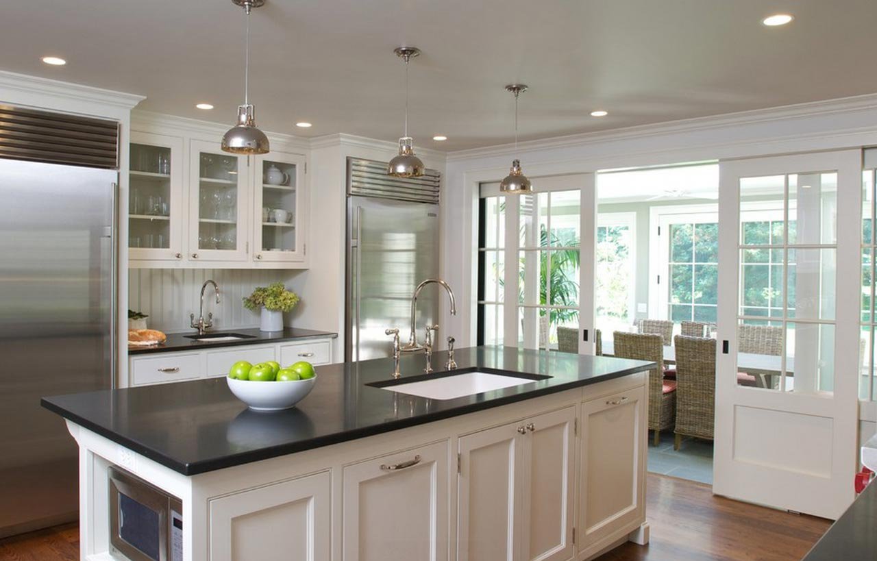 Bright kitchen view with a honed Absolute Black Granite island worktop, showing the matte black surface with a sink and tap set into the island.