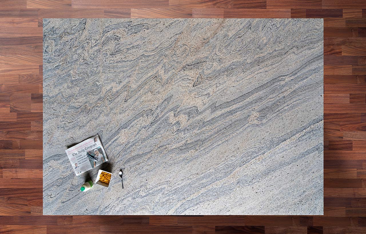 Overhead view of Ivory Wave Granite worktop showing flowing blue grey veining and natural movement, photographed from above with a small styled tray in the corner.