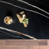 Noir St Laurent Porcelain worktop slab close up showing deep black surface with bold gold veining, styled with food and accessories