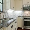 Traditional kitchen view with Sapphire Brown Granite worktops on cream cabinetry, showing the polished Granite surface around the sink and cooking area.