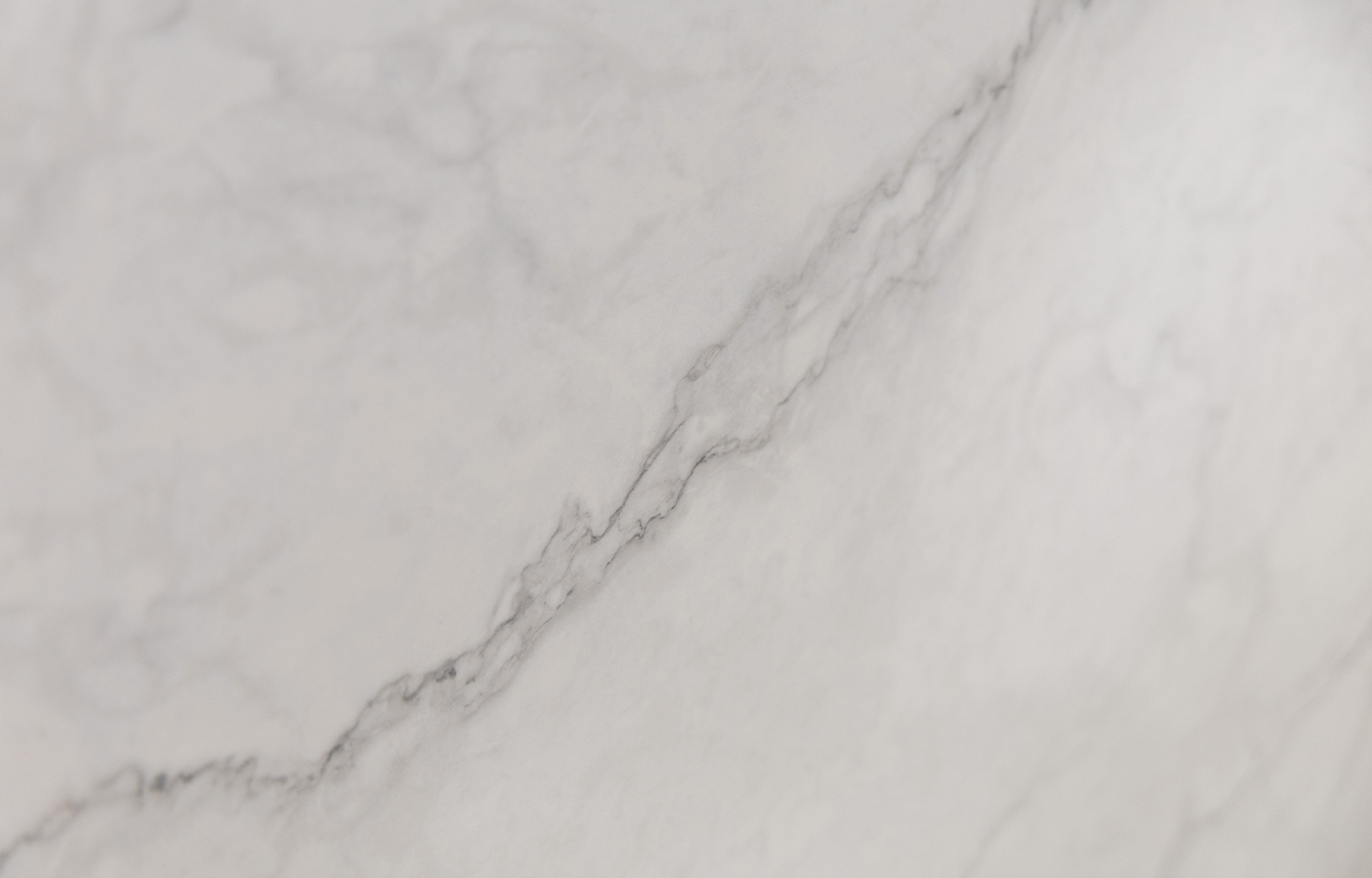 Statuario Venato Porcelain slab detail with a stronger grey diagonal vein and fine branching lines on a pale background.