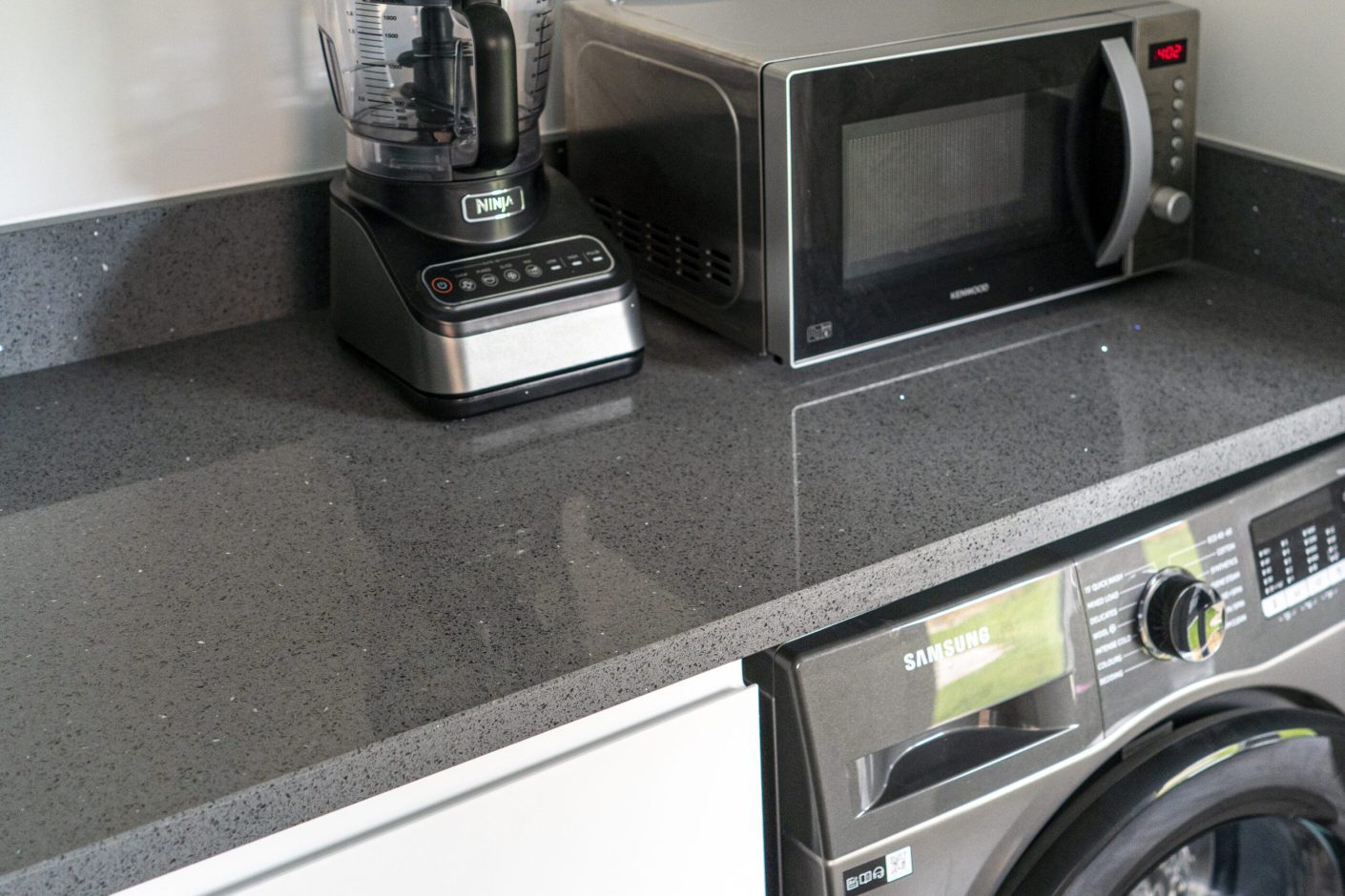 Grey Starlight Quartz worktop close-up with subtle sparkle flecks beside kitchen appliances