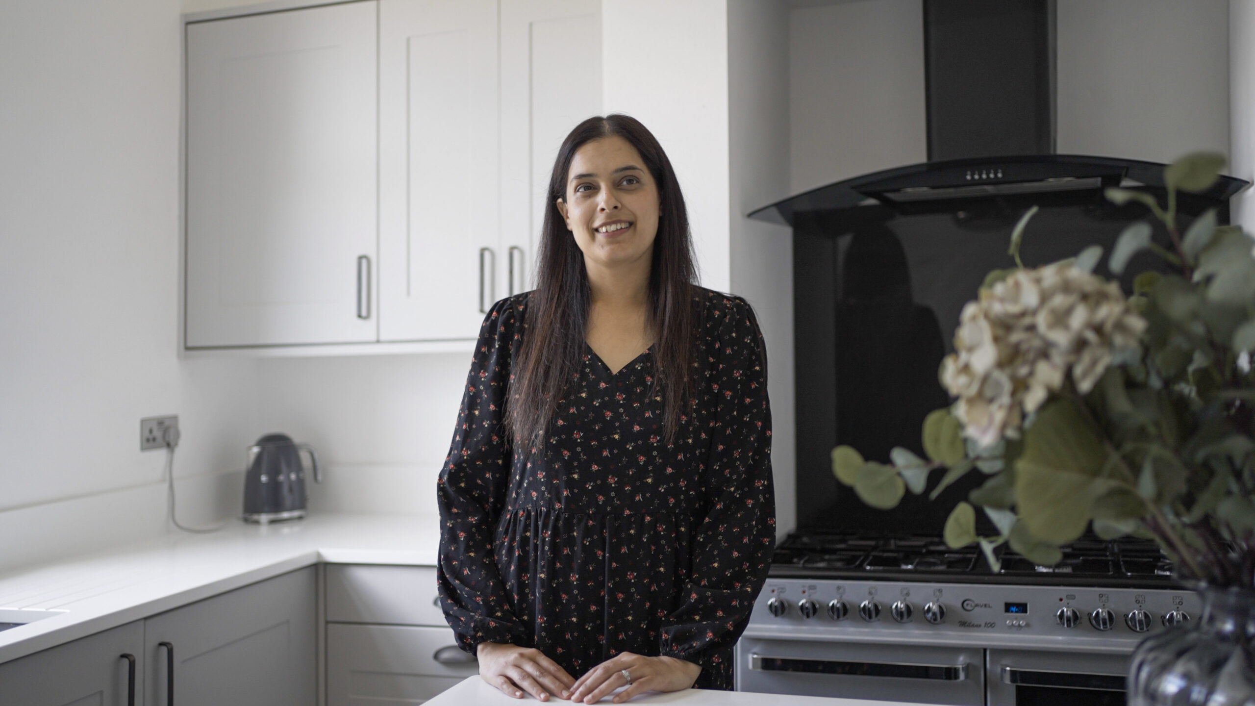 Nadiya customer testimonial image in her kitchen with Classic White Quartz worktops visible in the background