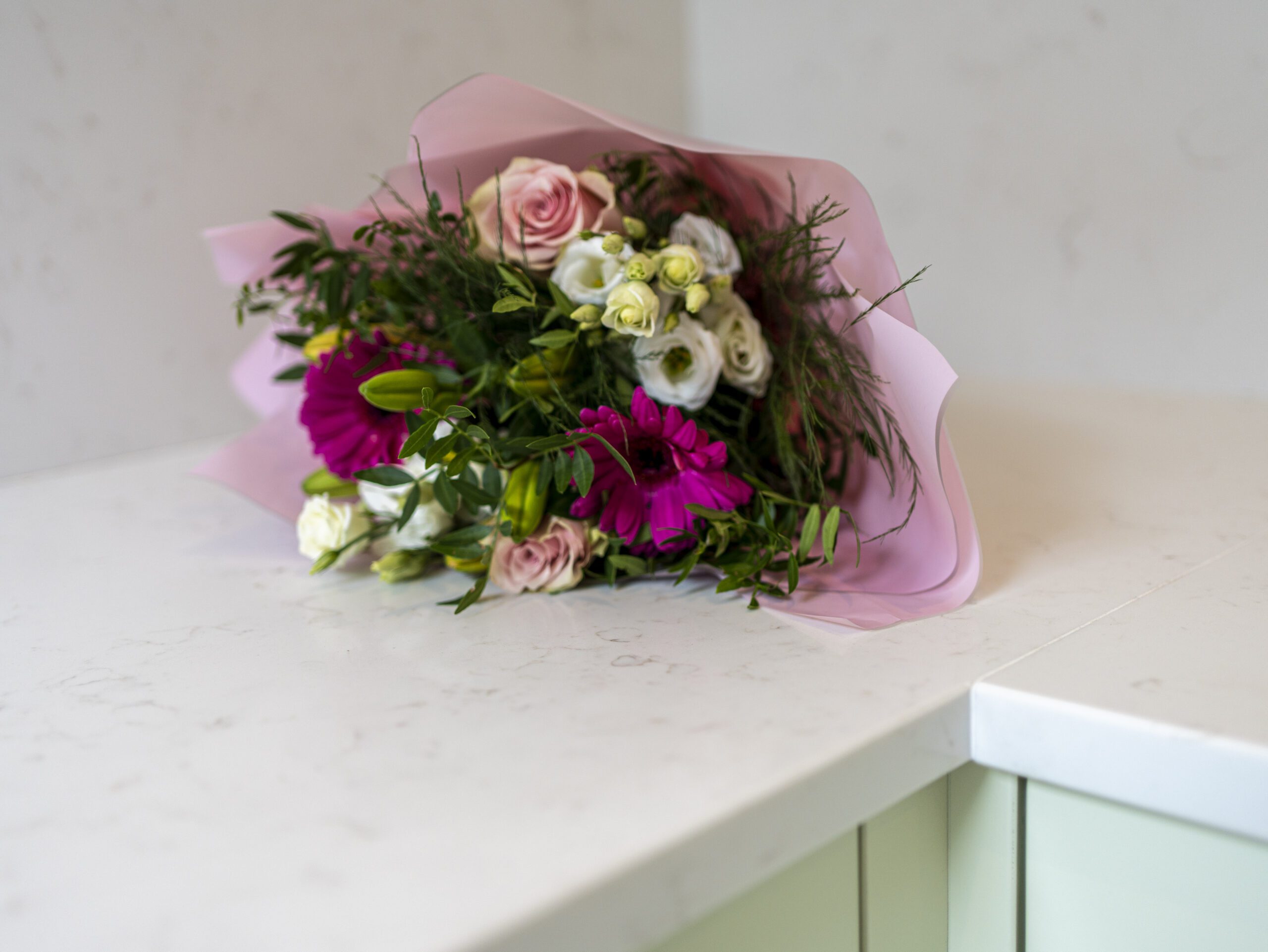 Flower bouquet placed on Carrara Quartz worktop in a pastel kitchen