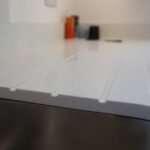 Close-up of Dover White Quartz drainer grooves showing clean channel lines and a smooth white finish