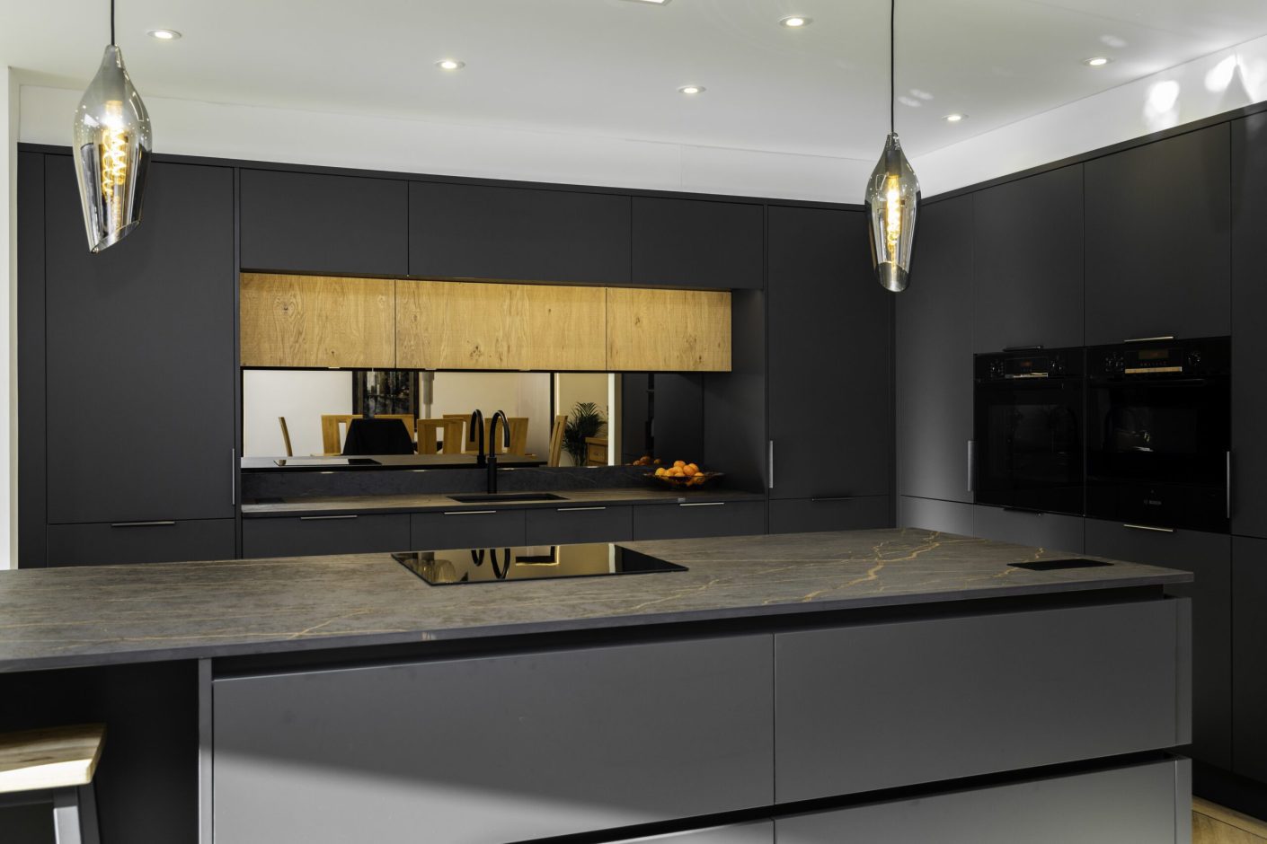 Wide view of a Laurent Porcelain worktop with gold veining on a large island, featuring a flush hob and pendant lighting.