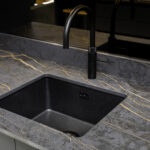 Laurent Porcelain worktop close-up showing an undermount black sink and black tap with gold veining through the surface.
