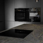 Laurent Porcelain worktop with gold veining fitted in a modern kitchen, featuring a flush black hob beside built-in ovens.