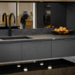 Laurent Porcelain worktop installed along the sink run with a black tap, sink and fruit bowl in a modern dark kitchen.