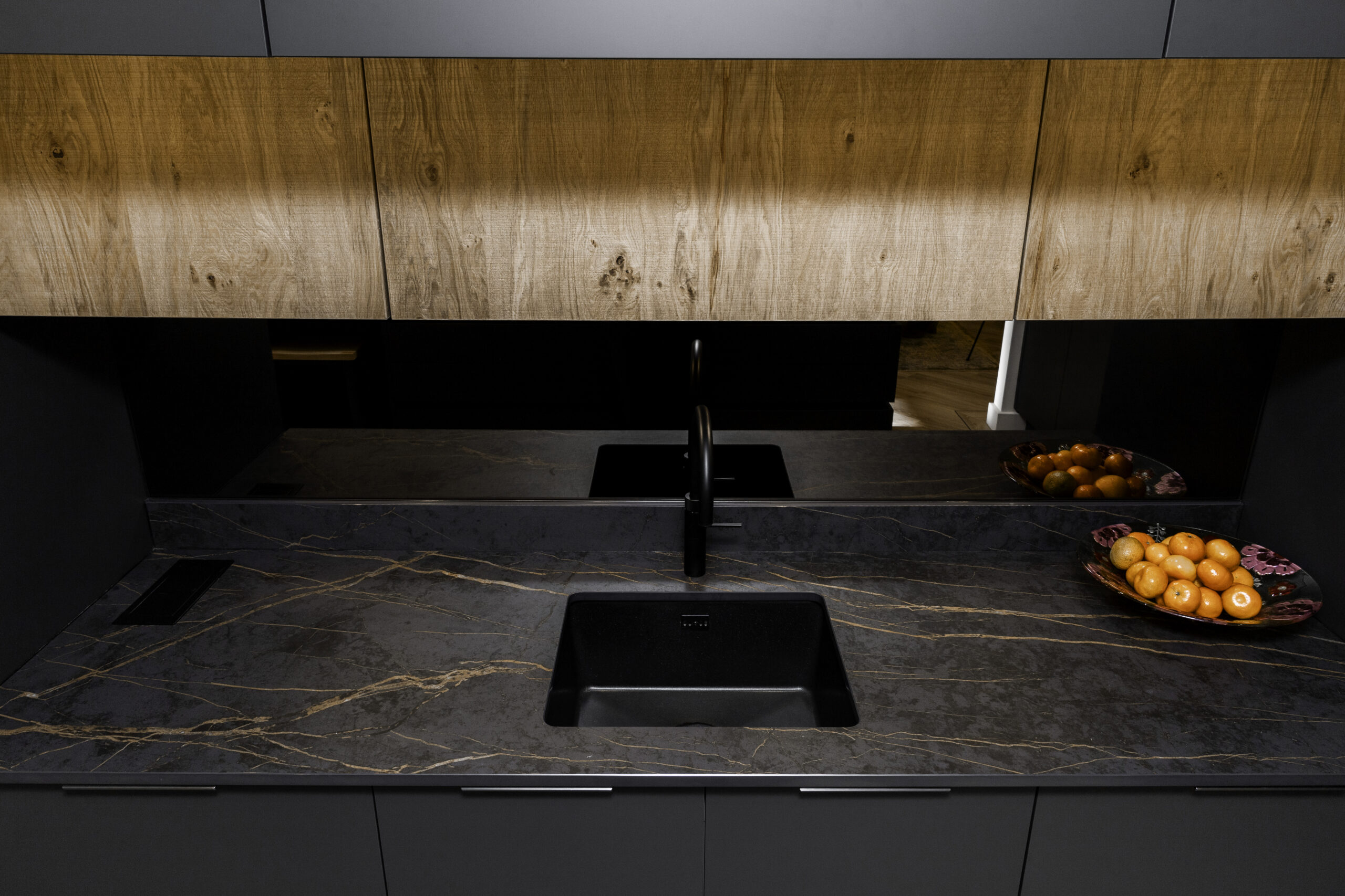 Laurent Porcelain worktop with gold veining, featuring an undermount sink and black tap beneath warm wood cabinetry.