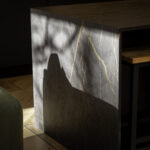 Laurent Porcelain waterfall end panel detail showing gold veining on a dark porcelain surface beside cabinetry.