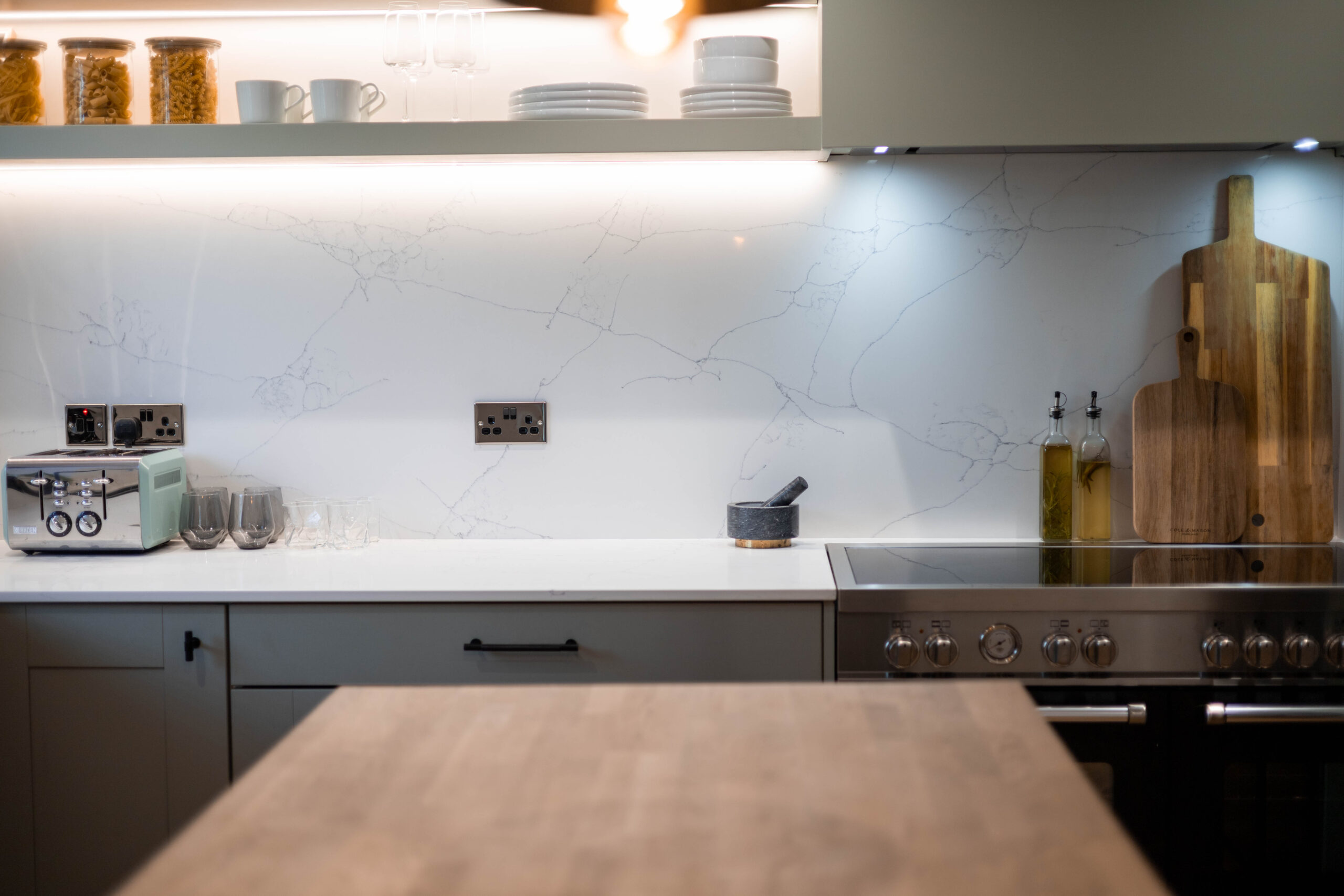 White Macaubus Quartz worktop run with subtle veining beneath under-cabinet lighting in a modern kitchen
