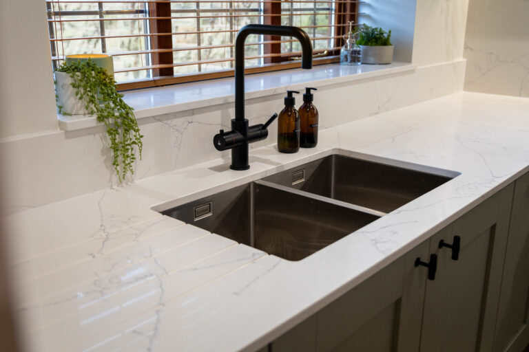 White Macaubus Quartz worktop with an undermount sink and black tap, showing subtle grey veining