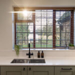 White Macaubus Quartz sink run with an undermount sink and black tap, shown beneath a large window