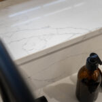 White Macaubus Quartz worktop close-up showing subtle veining and a clean edge beside kitchen bottles