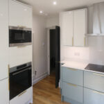 Dover White Quartz worktop run with an induction hob in a modern kitchen with light cabinetry