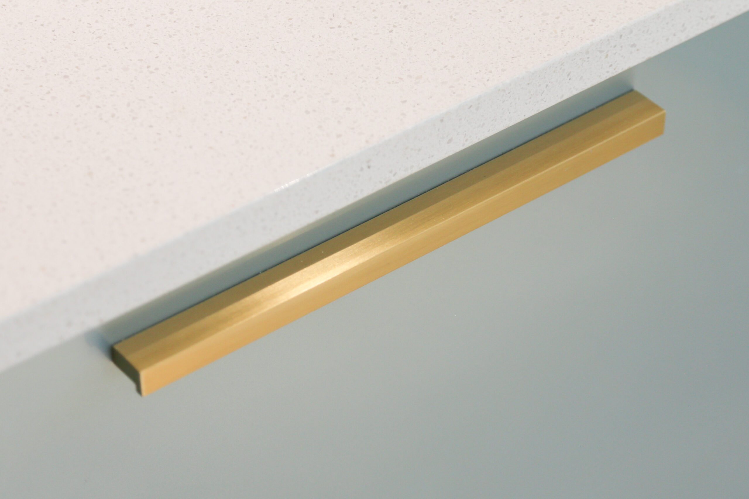 Dover White Quartz worktop edge close-up above pale green cabinetry showing a smooth white finish
