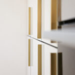 Dover White Quartz worktop edge close-up beside white cabinetry with gold handles