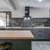 Trilium Porcelain worktop and full-height splashback installed in a modern kitchen with grey units and a timber breakfast bar.