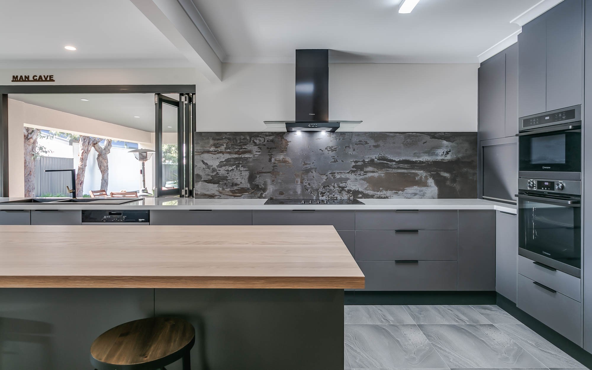 Trilium Porcelain worktop and full-height splashback installed in a modern kitchen with grey units and a timber breakfast bar.