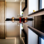 Low side angle of an Absolute Black Granite island worktop showing the polished edge and overhang with bottles and glasses on the worktop.