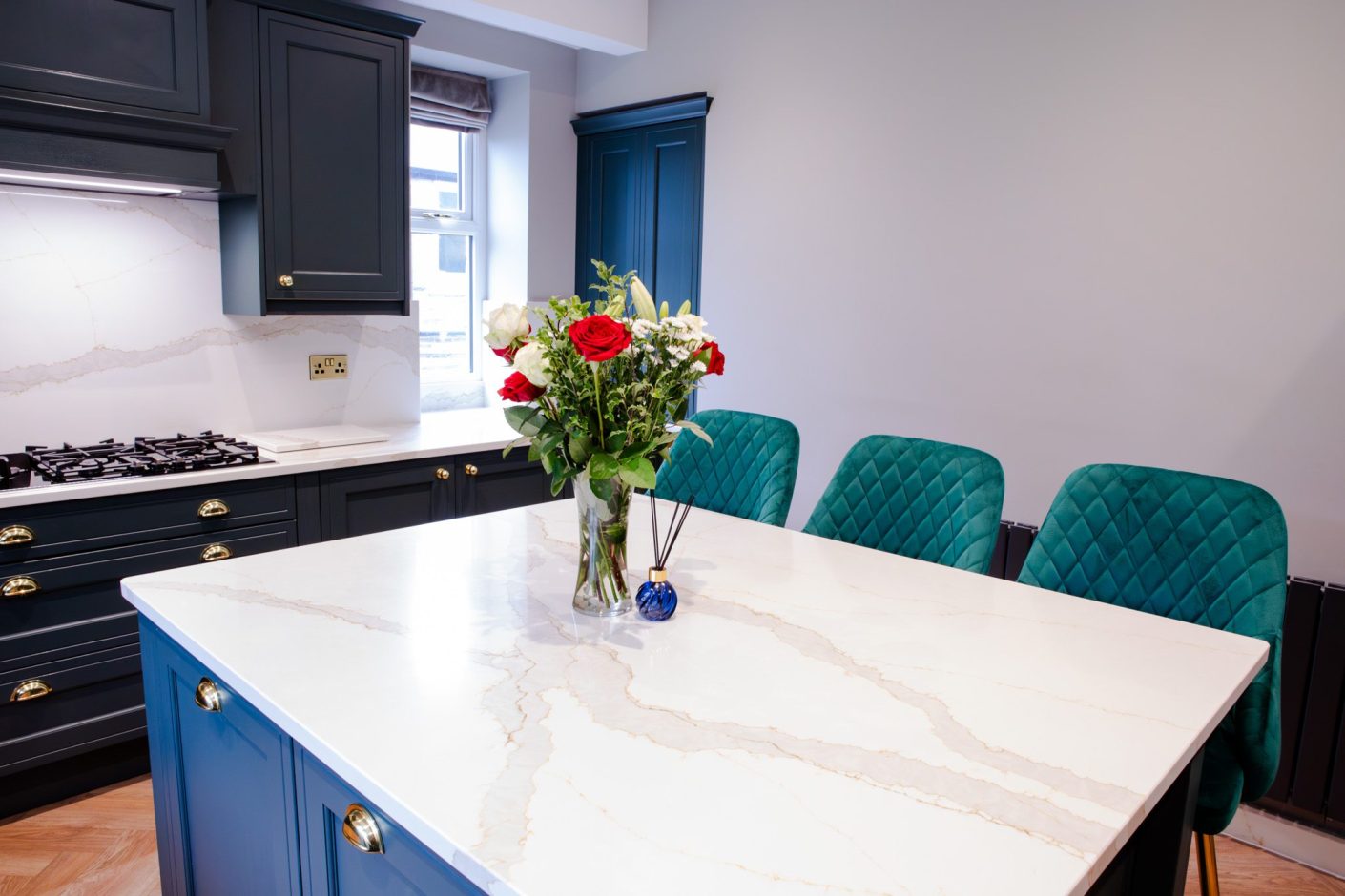 Britannicca Calacatta Quartz island worktop with seating showing flowing warm grey veining across the polished white surface