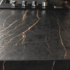 Laurent Porcelain worktop close-up showing dark stone-effect surface with strong gold veining under kitchen lighting.