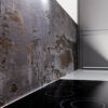 Trilium Porcelain splashback panel behind a ceramic hob with a worktop edge and light wall return visible on the right