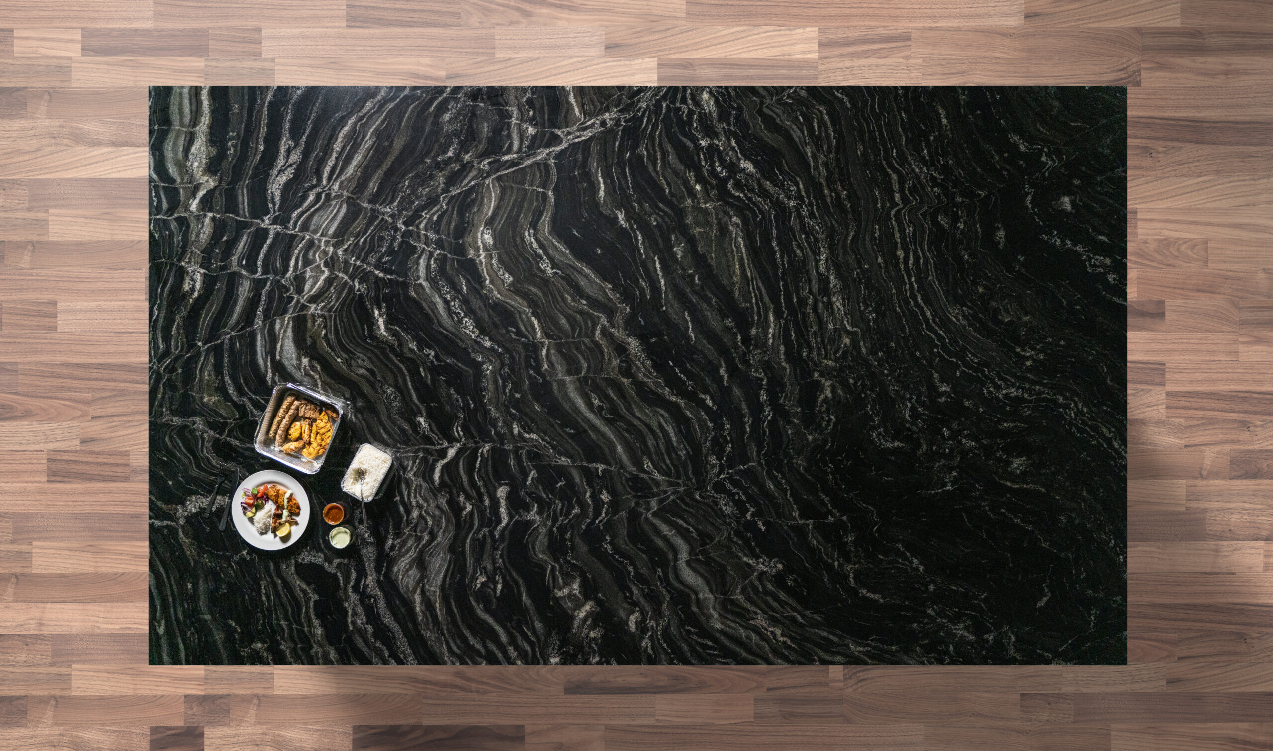 Overhead view of a Black Storm Granite island worktop showing bold natural veining, photographed from above with a small styled tray in the corner.