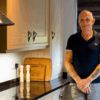 Testimonial video still of a customer standing in their kitchen after a Star Galaxy Granite worktop installation by Mayfair Worktops.