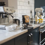 Arabescato Quartz worktop in a dark kitchen run showing grey veining beside small appliances and coffee items