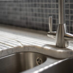 Close-up of Arabescato Quartz drainer grooves beside a stainless steel sink and tap showing grey veining