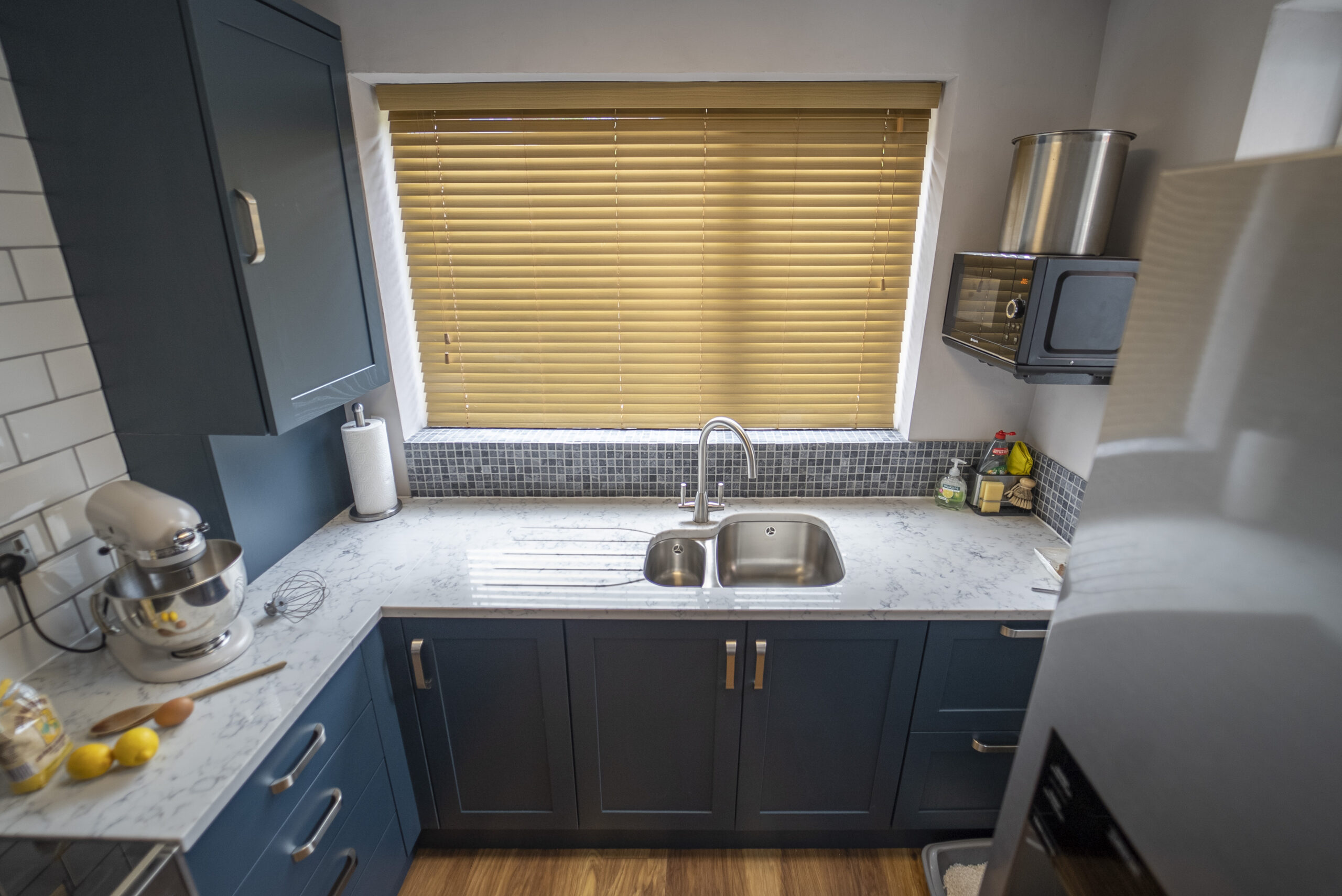 Overhead view of Arabescato Quartz worktops around a double sink in a kitchen with dark cabinets