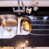 Sink area in Star Galaxy Granite with drainer grooves and a polished finish, showing the sparkling fleck pattern beside a stainless steel sink.
