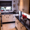 Wide view of a traditional kitchen with Star Galaxy Granite worktops on the perimeter run, showing the glossy black surface, sink area and light cabinetry.