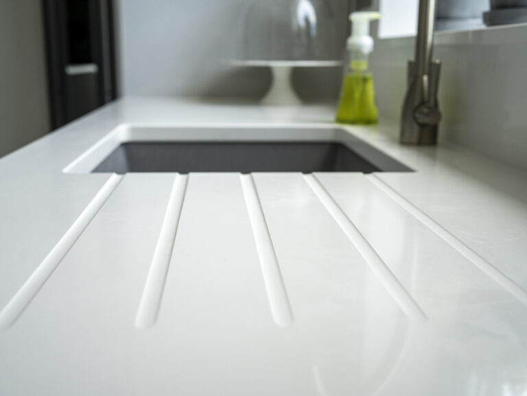 Classic White Quartz drainer grooves beside an inset sink, showing a smooth white surface finish