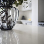 Classic White Quartz island worktop surface with a vase, showing a smooth white finish and light reflection