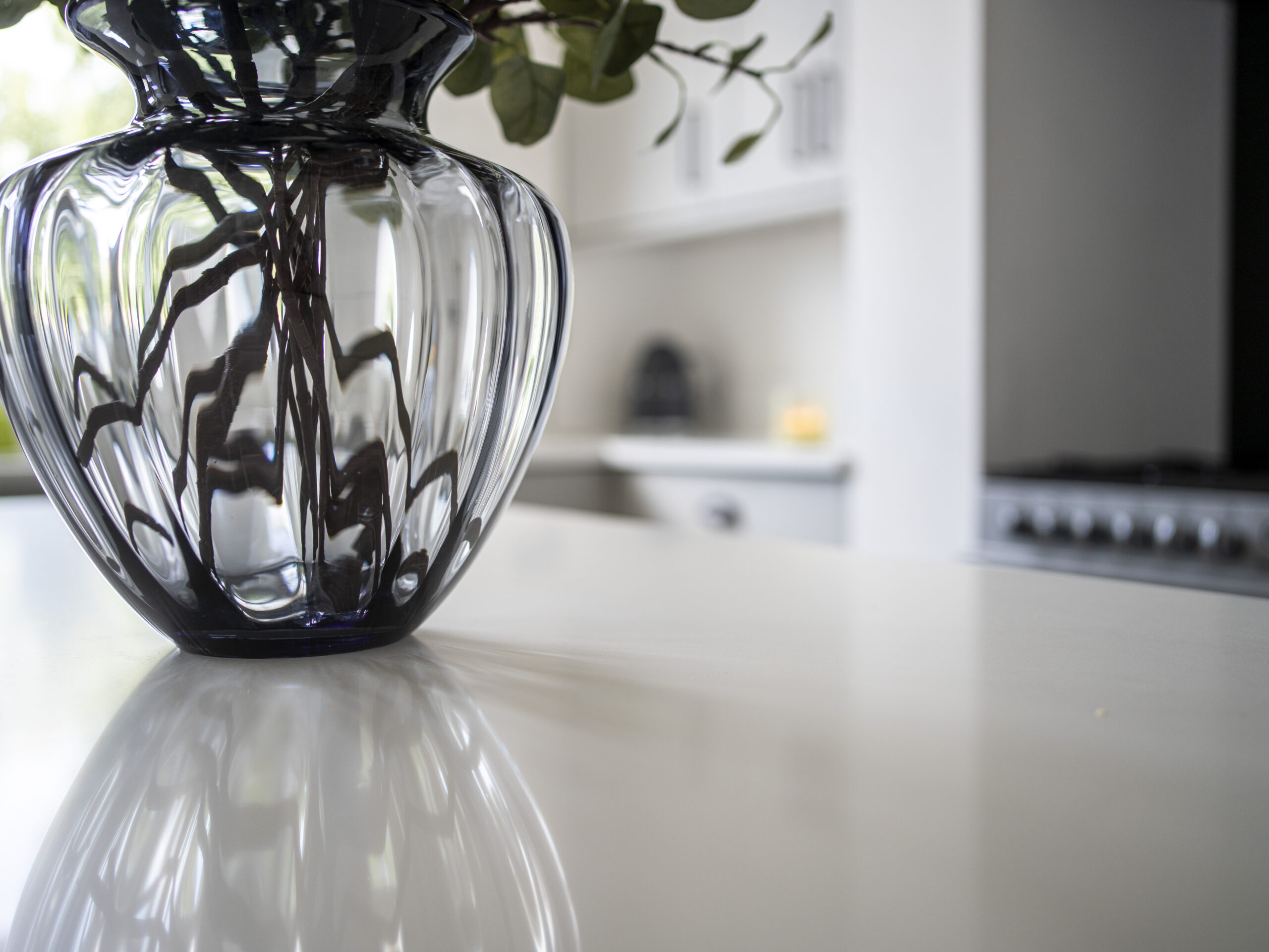 Classic White Quartz island worktop surface with a vase, showing a smooth white finish and light reflection