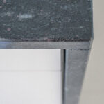 Close up of a Cosmic Black Granite worktop corner showing the polished edge profile and waterfall end detail above white cabinetry.