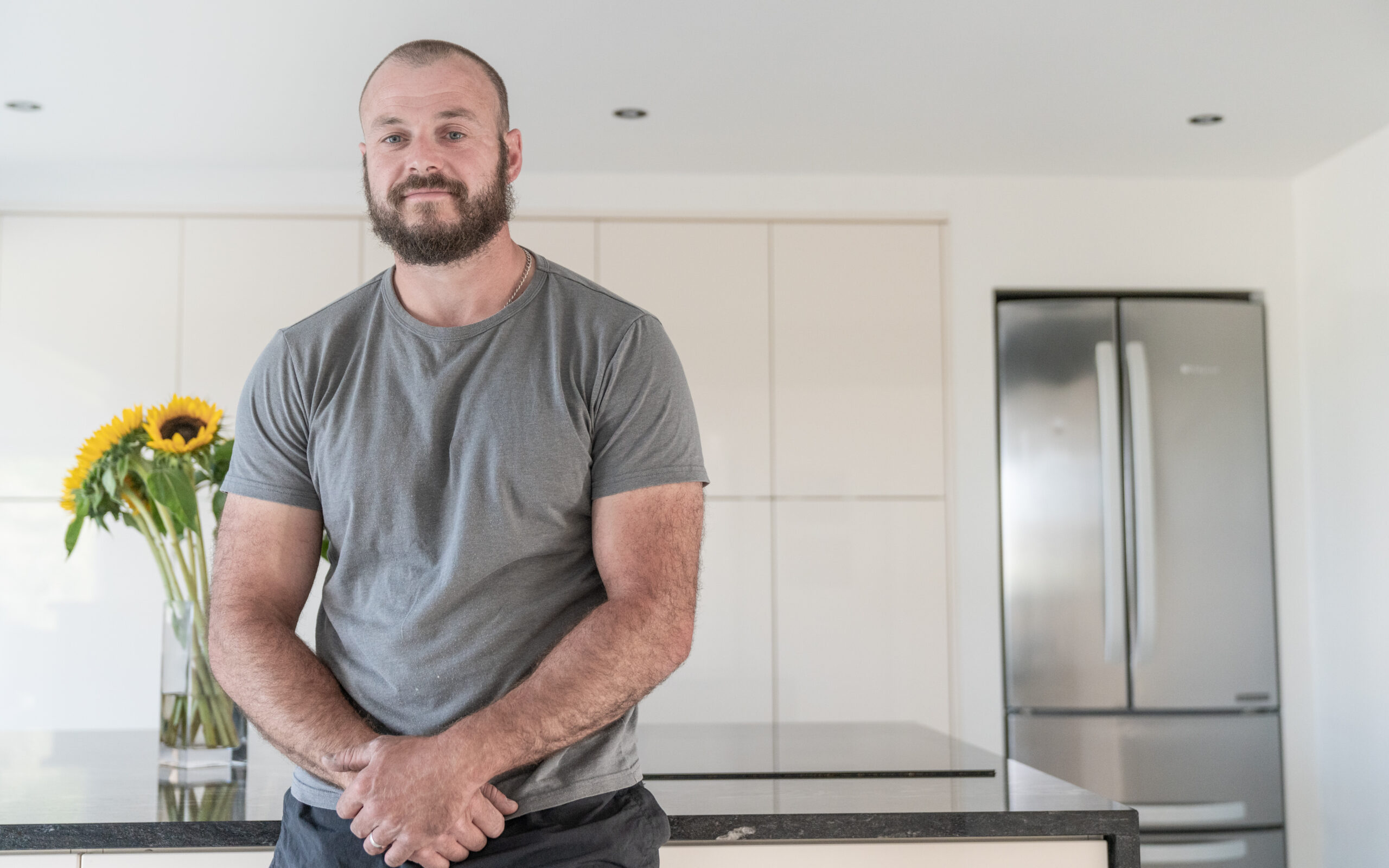 Testimonial video still of a customer speaking in their kitchen after a Cosmic Black Granite worktop installation by Mayfair Worktops.