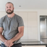 Testimonial video still of a customer speaking in their kitchen after a Cosmic Black Granite worktop installation by Mayfair Worktops.