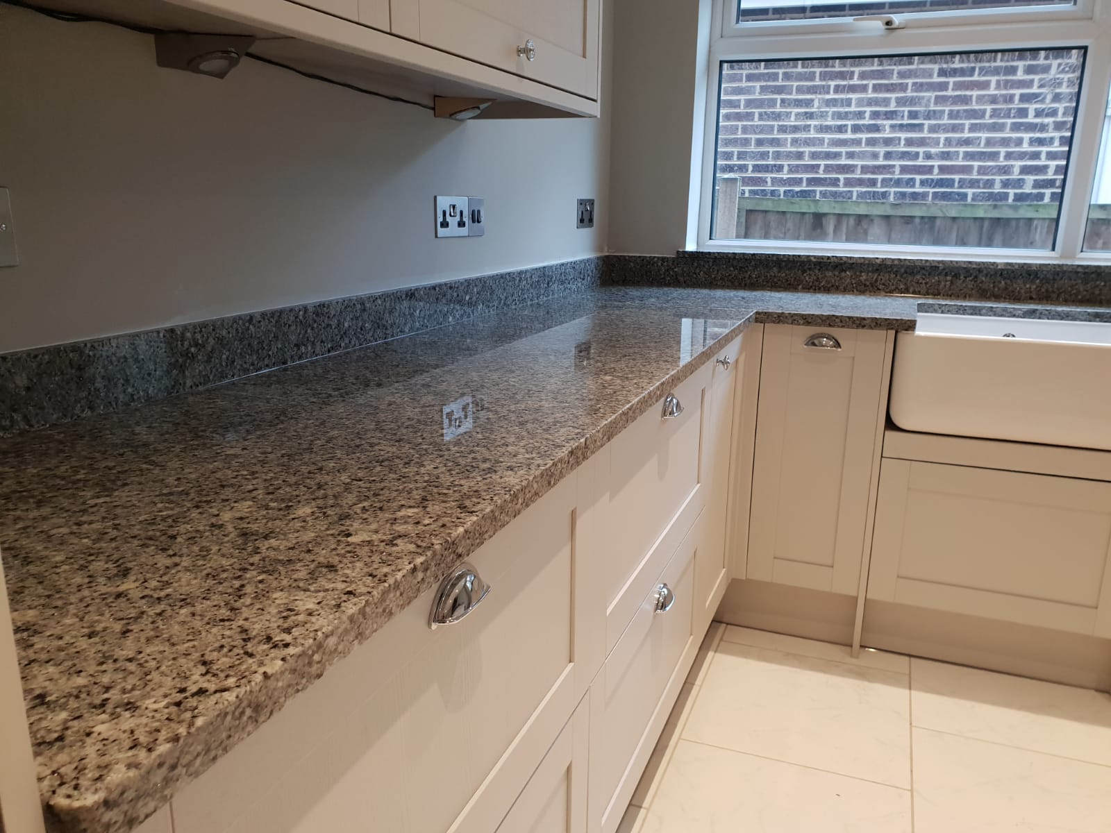 Worktop run in Azul Platino Granite on light cabinetry, showing the polished speckled Granite surface along the wall with a clean straight edge profile.