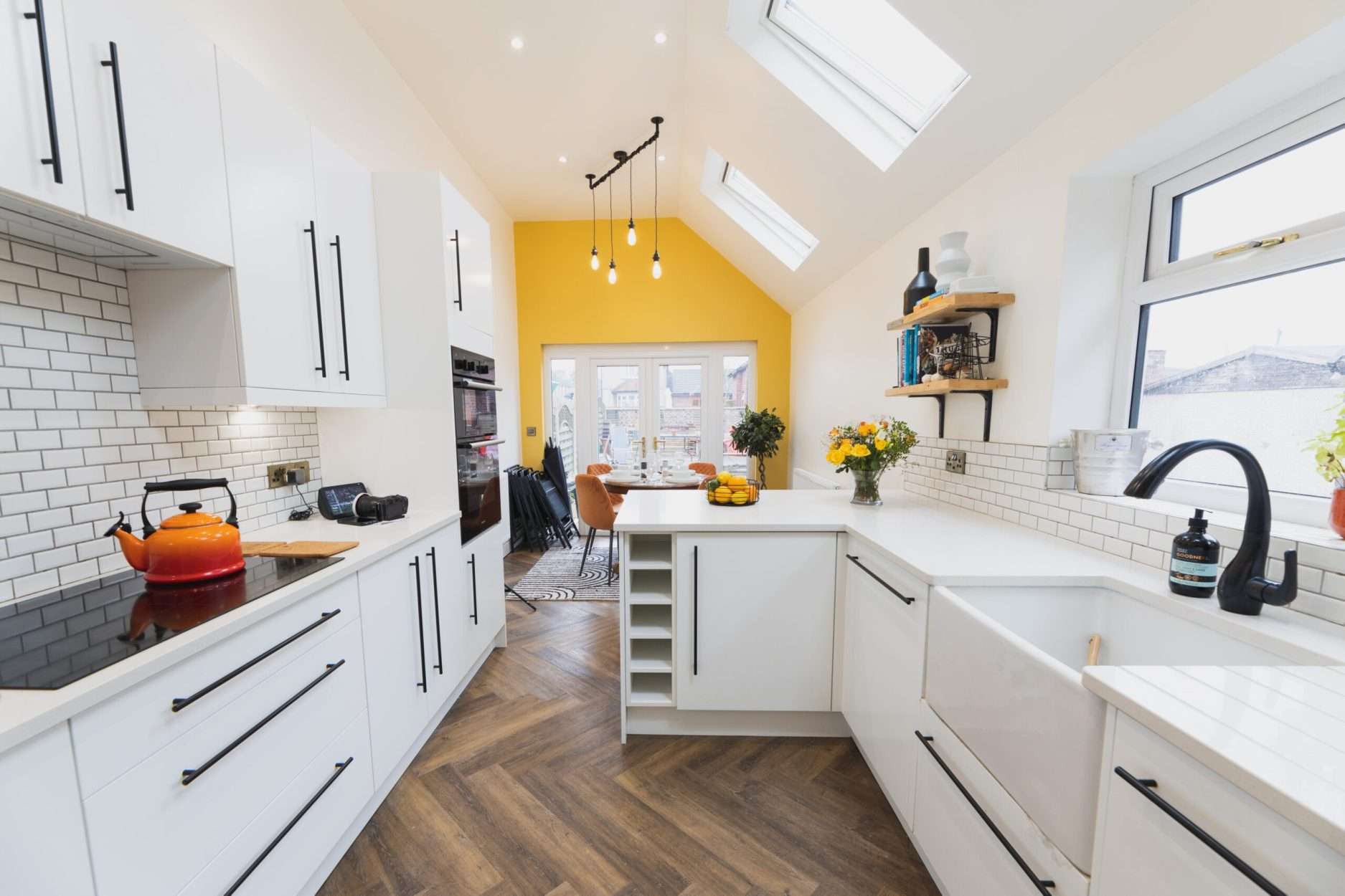 Long kitchen perspective showing Ice White Quartz worktops along white cabinets with a bright, smooth finish