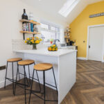 Ice White Quartz breakfast bar island with bar stools in a bright kitchen, showing a smooth white surface finish